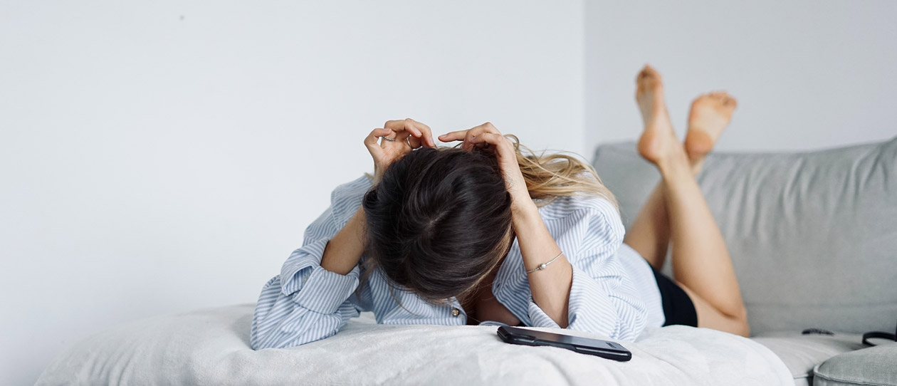 Woman in a grey shirt lying on a bed