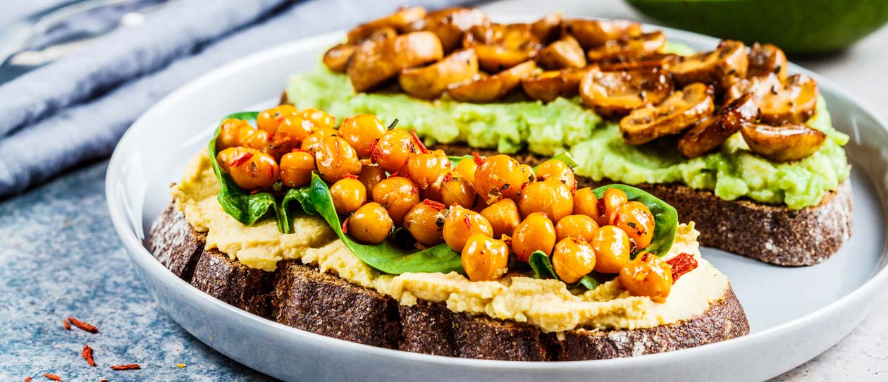 Vegan toasts with hummus and chickpeas, guacamole and mushrooms on rye bread.