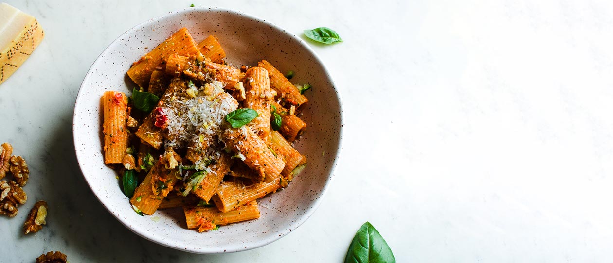 Bowl of penne pasta on a white bench