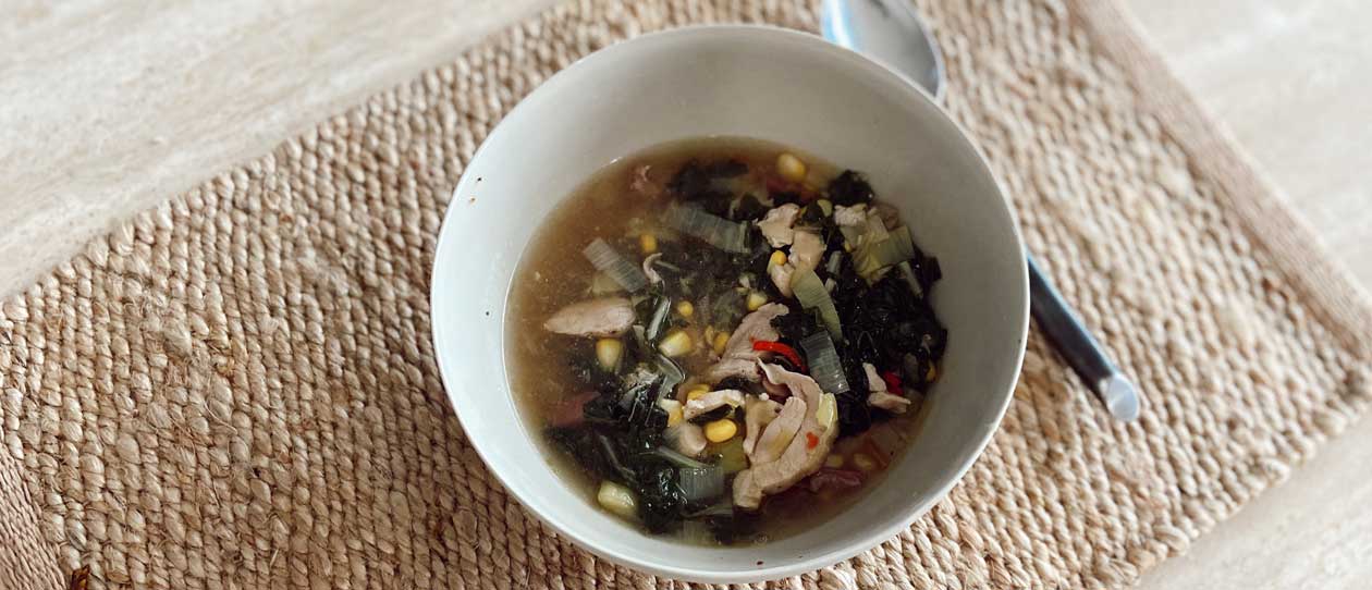 Bowl of chicken soup on a woven place-mat 