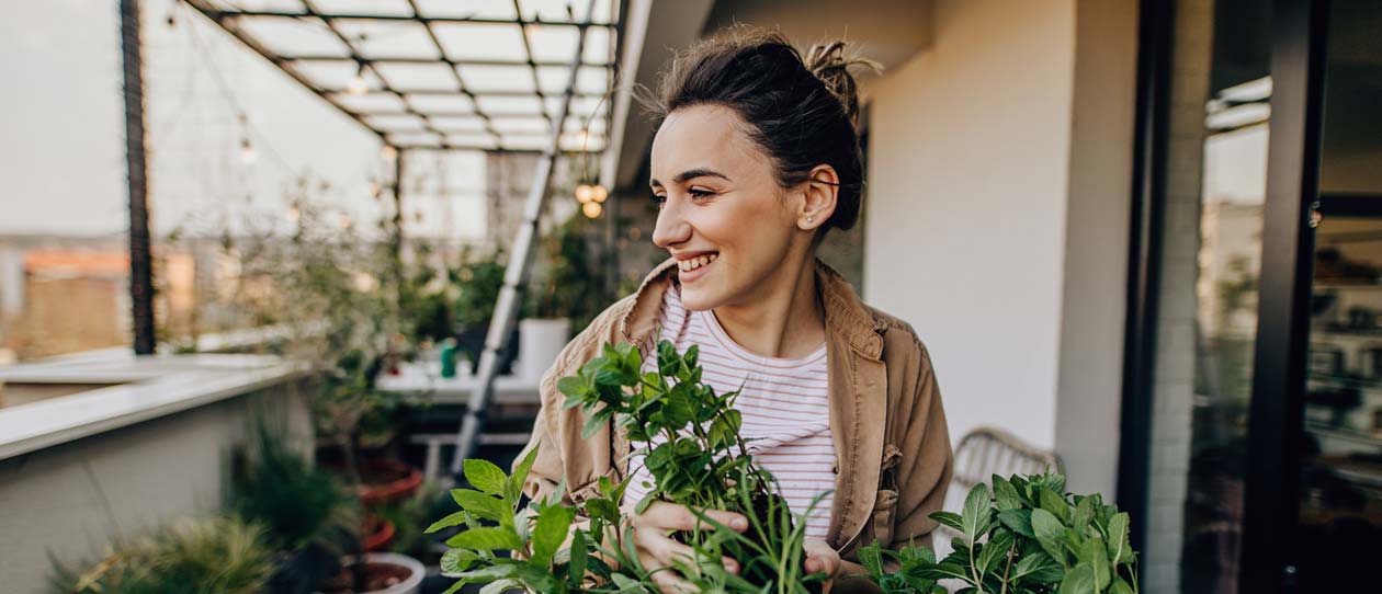  Young woman taking care of the plants in her rooftop garden